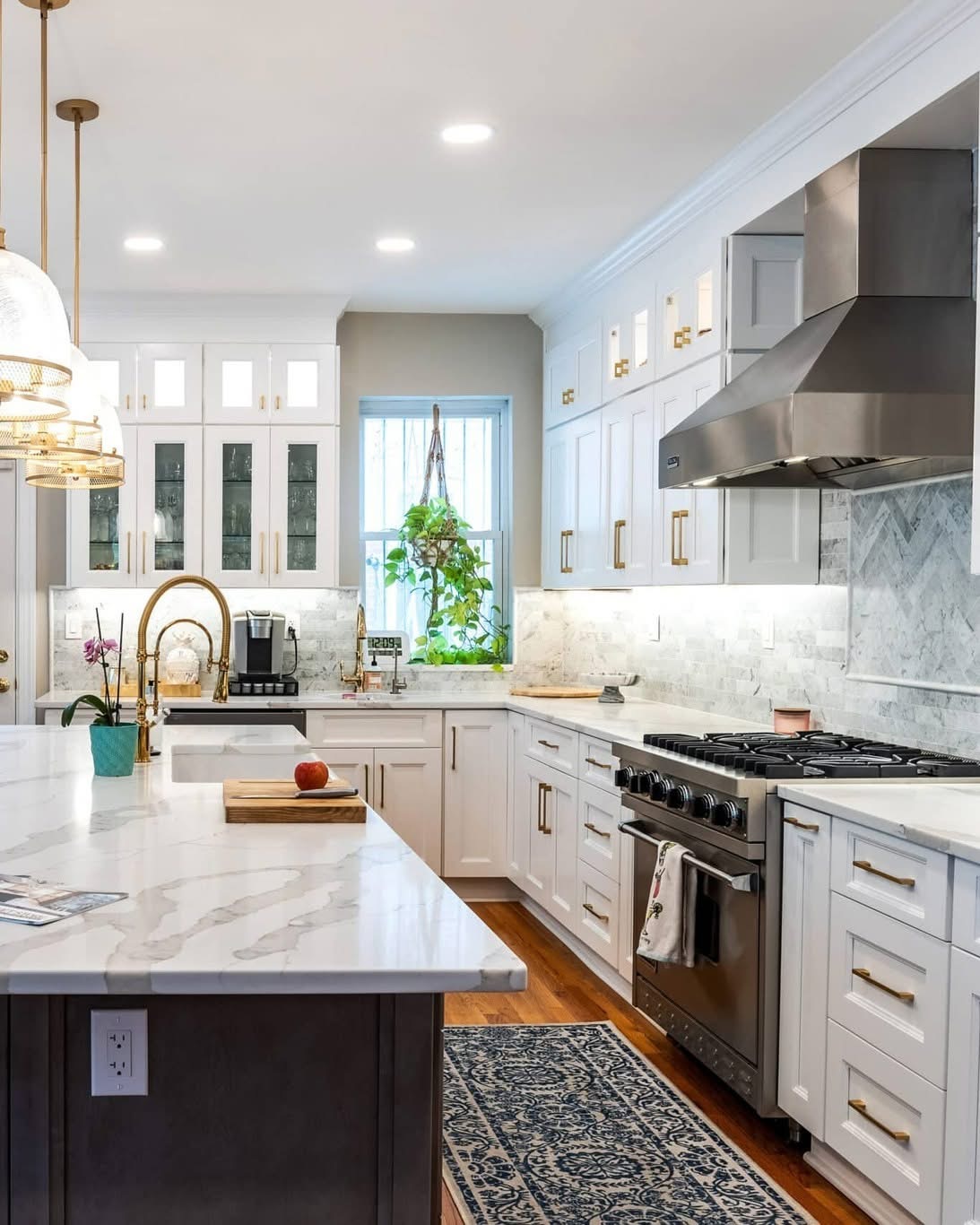 After: Finished kitchen featuring white shaker cabinets, charcoal island, and brass pendant lighting
