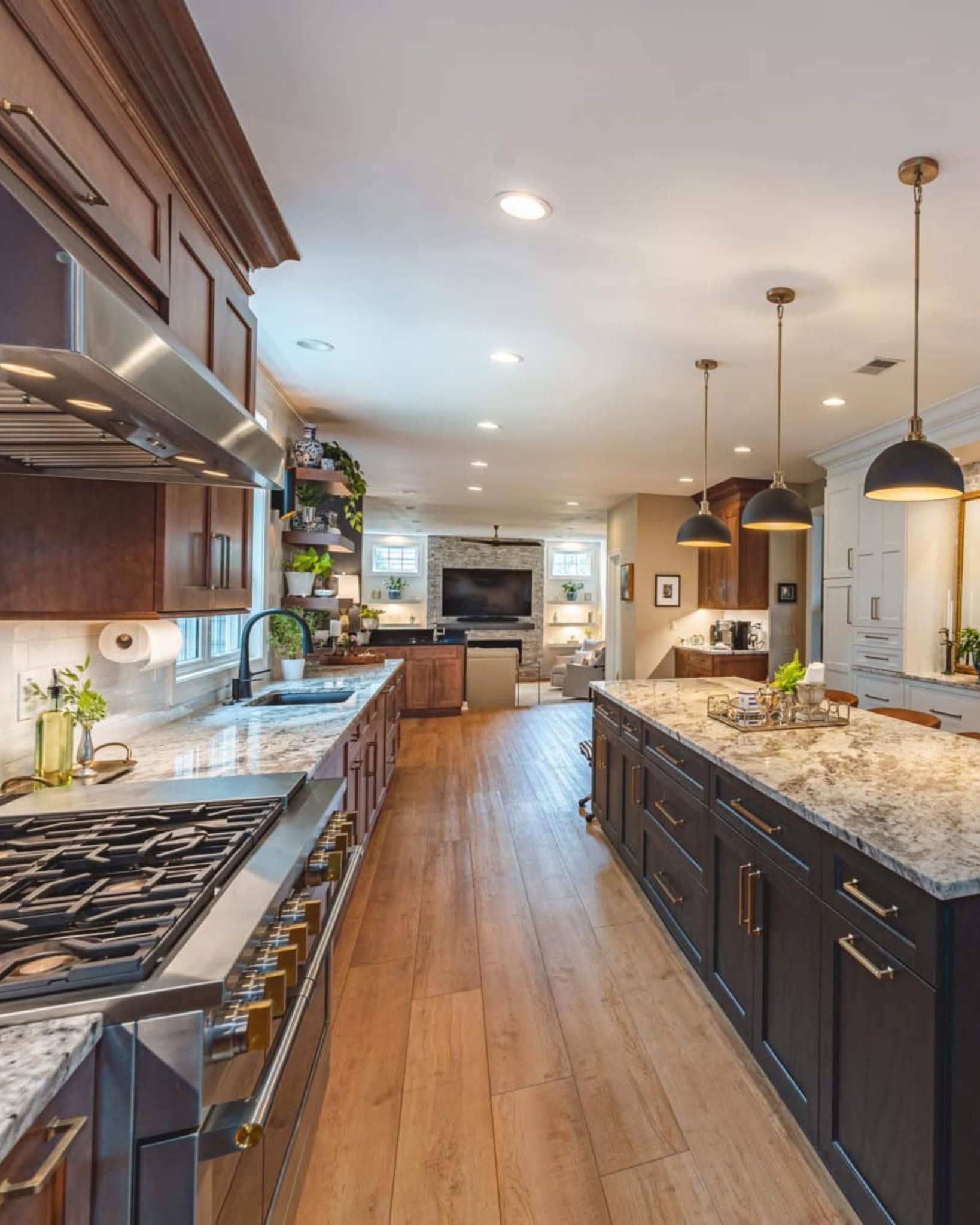 Before: Finished kitchen featuring white shaker cabinets, charcoal island, and brass pendant lighting